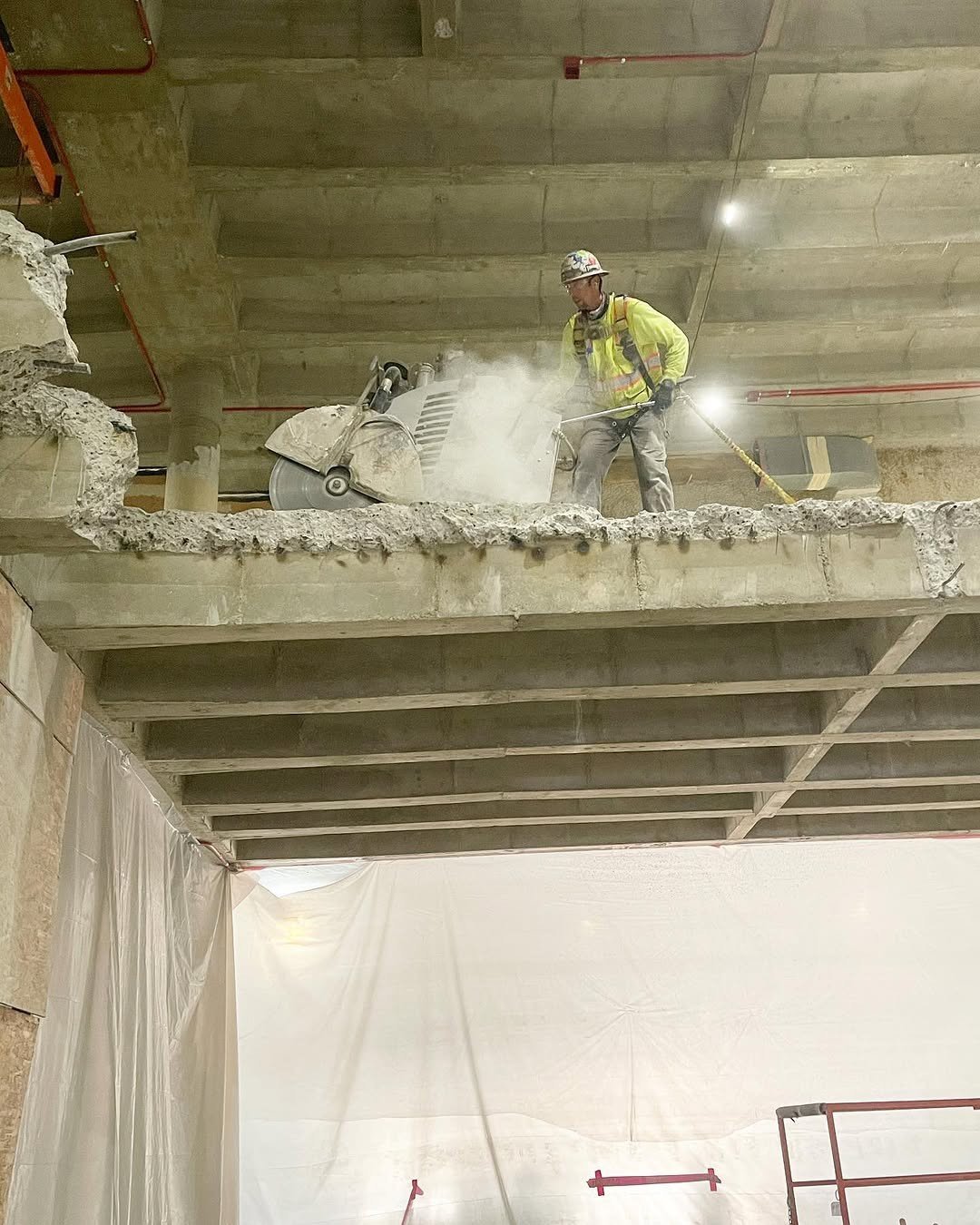 Diamond blade flat saw cutting through reinforced concrete slab with sparks flying